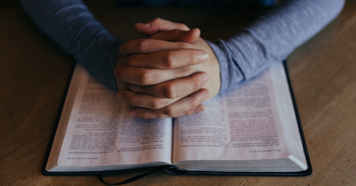 Hands praying over a Bible Hands praying over a Bible