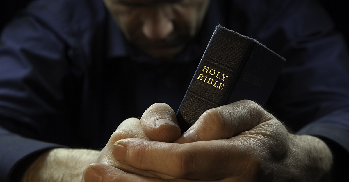 man_praying_holding_Bible | Wycliffe_Associates | Bible translation