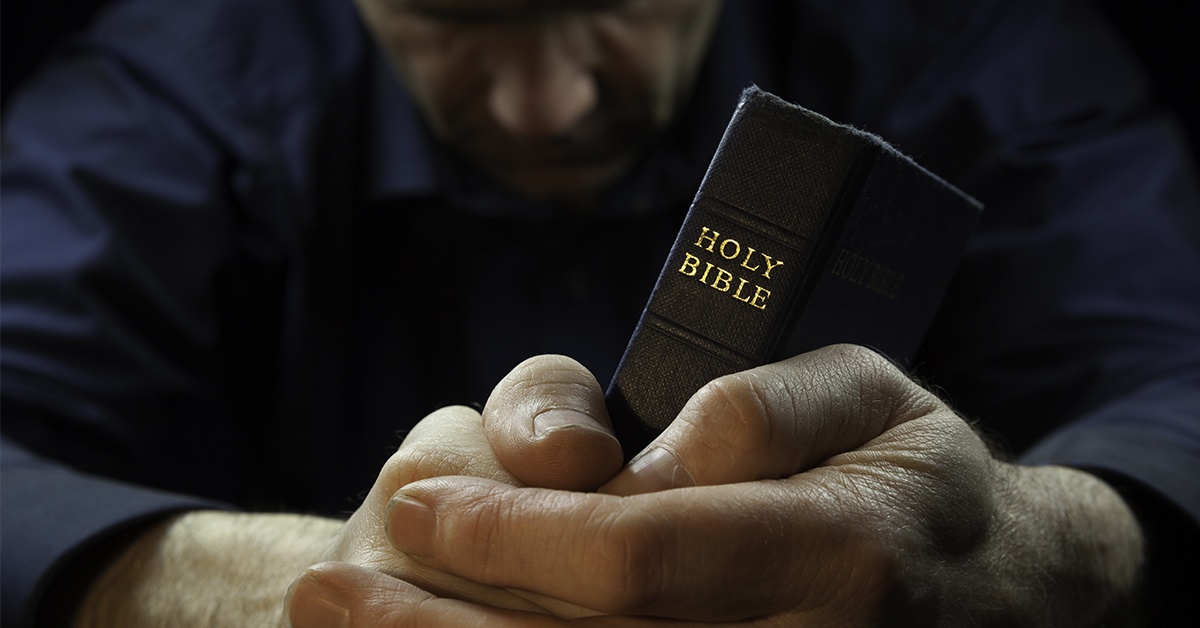 man praying holding Bible | Wycliffe Associates Accelerating Bible Translation