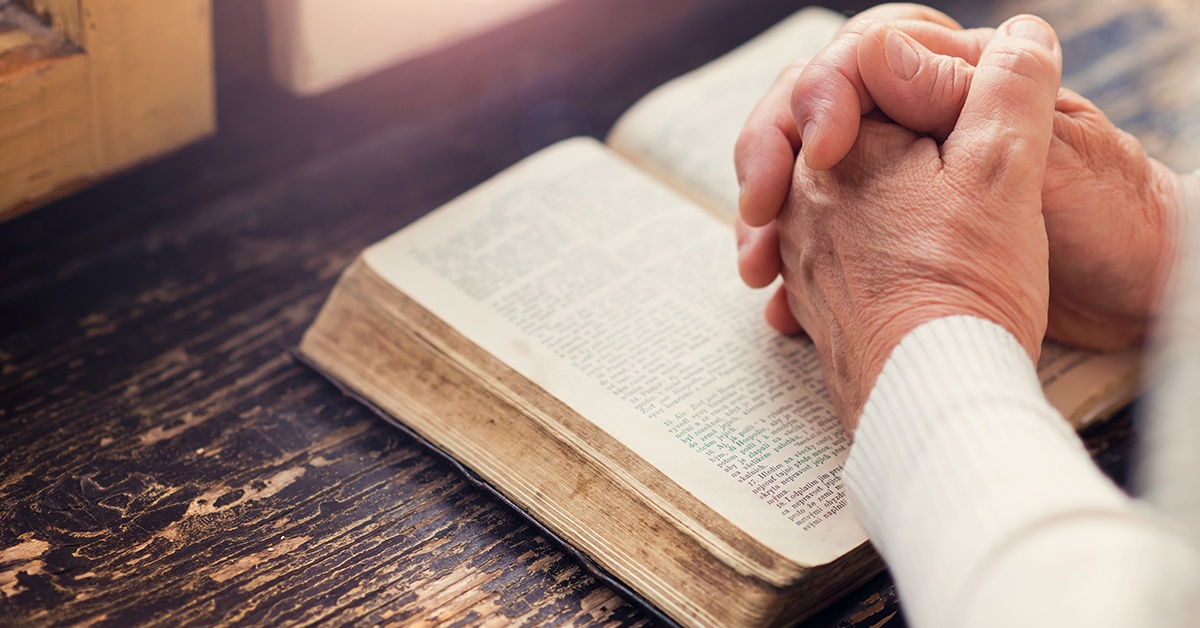 mature_woman_praying_hands_on_Bible | Wycliffe Associates | Bible Translation | Print On Demand