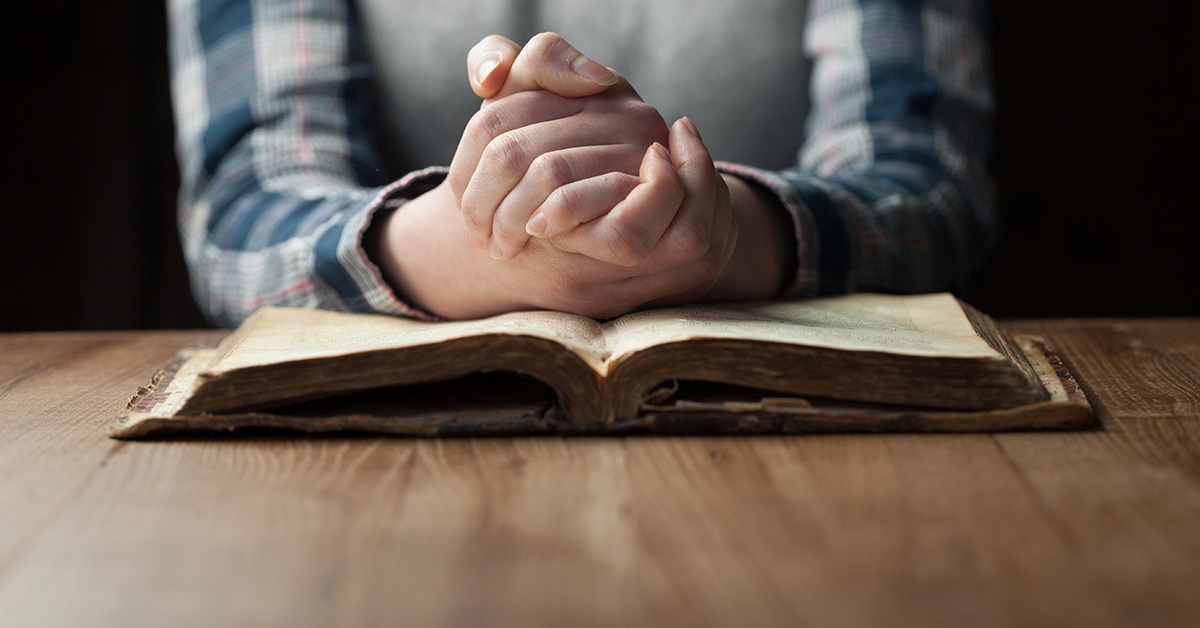 Praying hands on a Bible